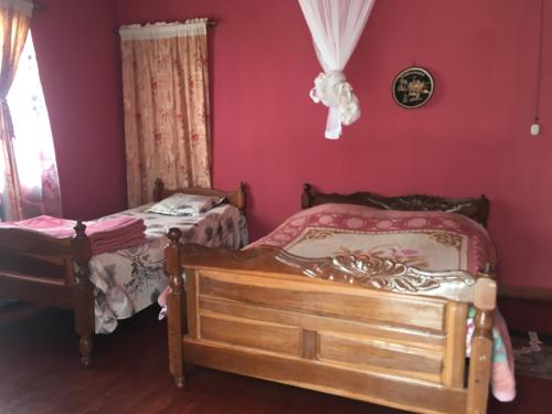 two beds in a room with red walls at Antsaly in Antananarivo