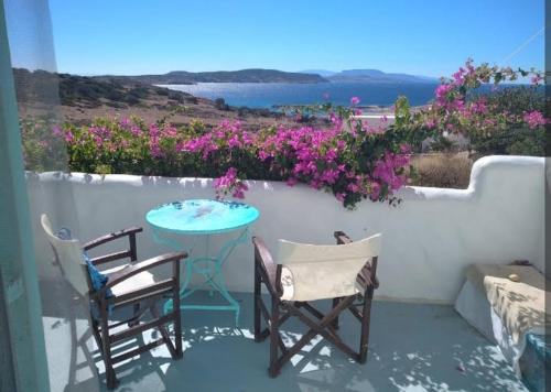 a patio with a table and two chairs and flowers at Λιογερμα in Koufonisia
