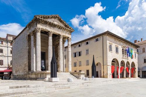 an ancient building with a column in front of a building at DV Apartment in Pješčana Uvala 