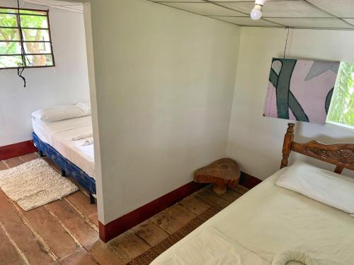 a small room with two beds and a window at Monkey House Hostel in Tola
