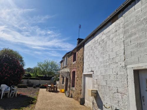 un vieux bâtiment en briques avec un chemin à côté de celui-ci dans l'établissement Gite Mont Saint Michel Chez Pépé Lucien, à La Gohannière