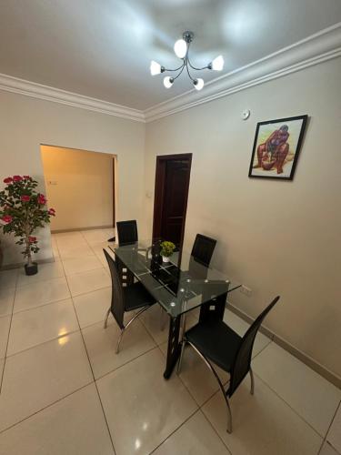 una sala da pranzo con tavolo e sedie in vetro di St Georges Apartment a Accra