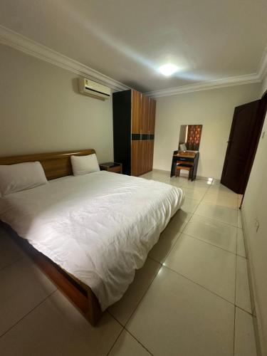 una camera da letto con un grande letto bianco e una scrivania di St Georges Apartment a Accra