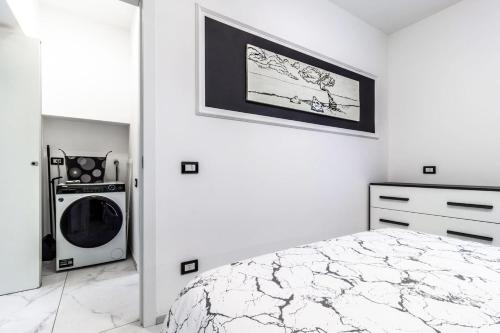a white bedroom with a bed and a washing machine at Black & White Apartment Design e Comfort - Parking e WiFi in Saronno