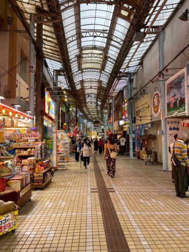 an indoor market with people walking in the middle of it at Hakka 沖縄 in Naha