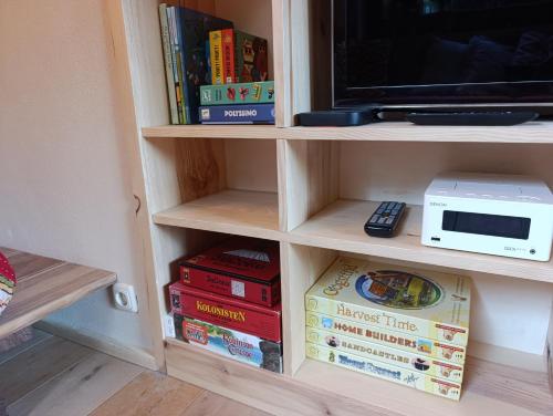 a book shelf filled with books and a tv at Juneberry Ecolodge Bergen in Bergen