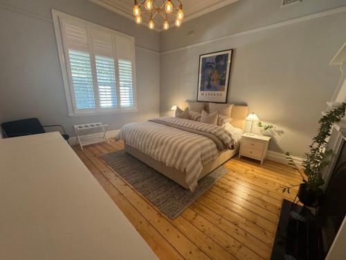 a bedroom with a bed and a chandelier at Olinda Cottage - CBD Bendigo with city views in Quarry Hill