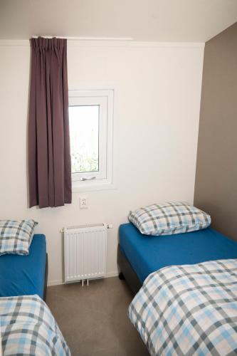 a room with two beds and a window at chalet beige in Serooskerke