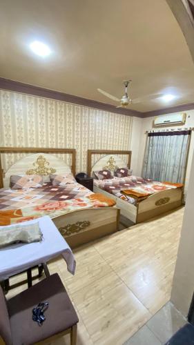 a bedroom with two beds and a table in it at Citi Hotel & Community Club in Faisalabad