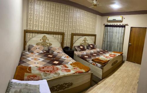 two beds are in a room with at Citi Hotel & Community Club in Faisalabad