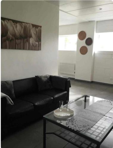a living room with a black couch and a coffee table at Ocalm gîte B-2h wellness par nuitée à réserver in Libramont
