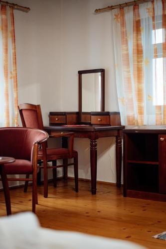 a dressing table with a mirror and chairs in a room at Abásfalvi Vendégházak in Aldea