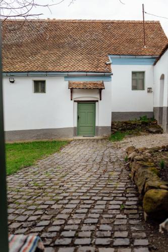 a building with a green door on a cobblestone street at Abásfalvi Vendégházak in Aldea