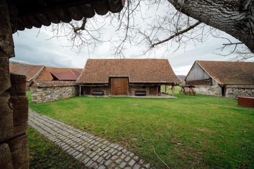 an old stone house with a grass yard and a building at Abásfalvi Vendégházak in Aldea