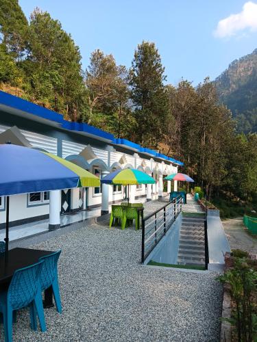 a patio with tables and umbrellas on a building at Hotel HBH Himalaya's Beautiful Hills in Uttarkāshi