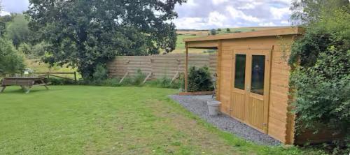 a small wooden shed in a yard with a bench at Ocalm gîte B-2h wellness par nuitée à réserver in Libramont