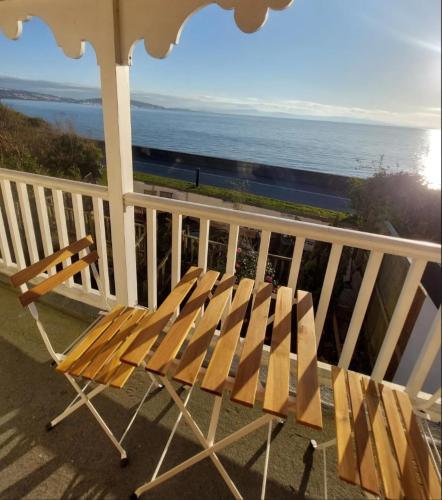 a wooden bench sitting on a balcony overlooking the ocean at Velo Club Mumbles in Oystermouth