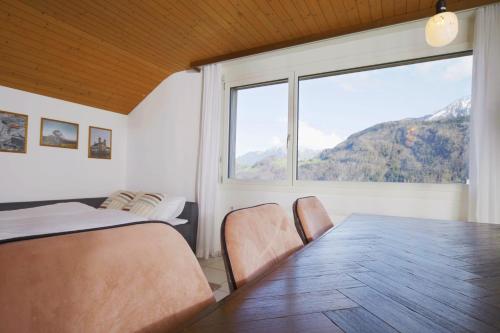 a bedroom with a table and a large window at Traumhafte 2,5-Zi-Wohnung mit Sicht auf den See in Alpnachstad