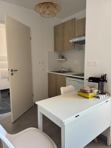 une cuisine avec une table blanche et un comptoir blanc dans l'établissement Appartement cozy proche du centre Terrasse,Parking, à Montpellier