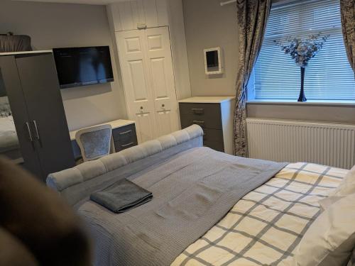 a bedroom with a bed and a television and a window at Manley House - Close to Town Centre - Self-Check-In - Driveway Parking, Two Living Rooms, Garden Office, Smart TVs by Yoko Property in Leigh
