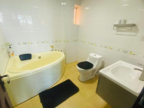 a bathroom with a tub and a toilet and a sink at Skylar H & Apartment in Dar es Salaam