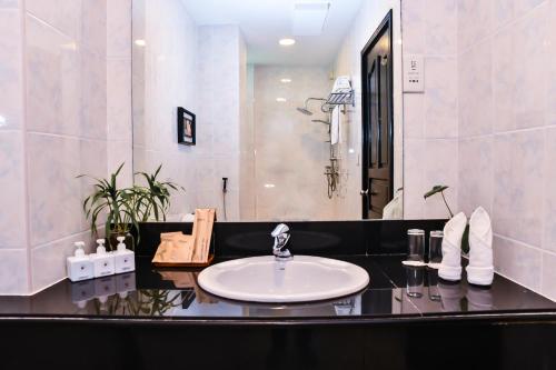a bathroom with a sink and a large mirror at The Beehive in Male City