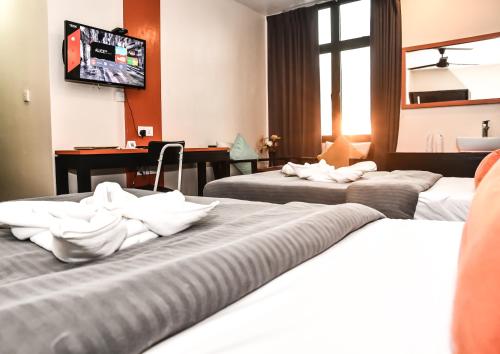 a hotel room with three beds and a television at The Beehive in Male City
