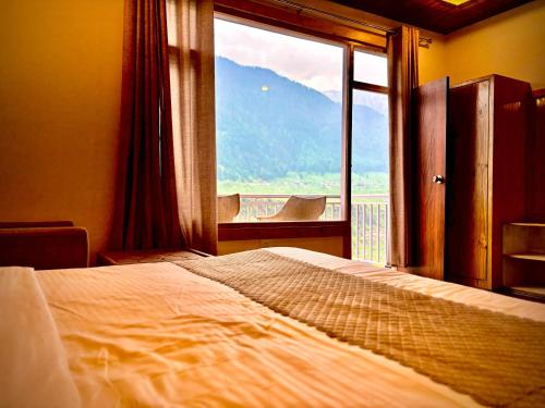 a bedroom with a bed and a large window at Orchard Heights, Manali in Jagatsukh