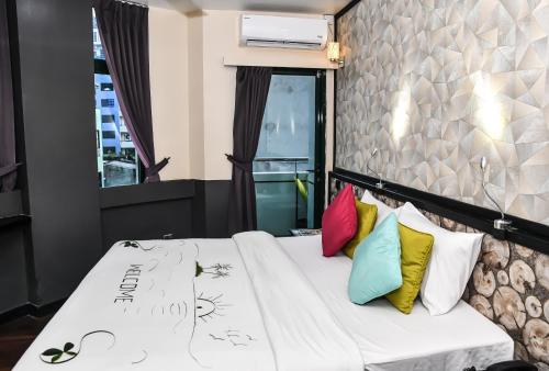 a bed with colorful pillows on it in a room at The Beehive in Male City