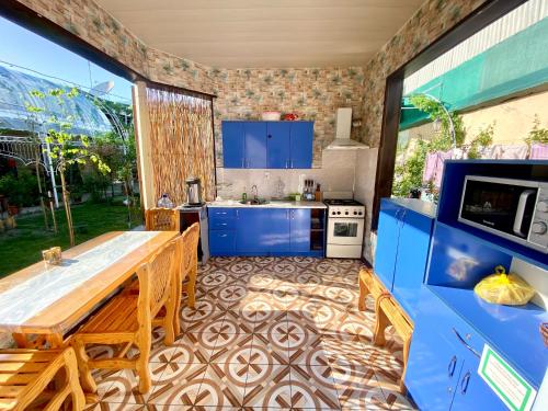 a kitchen with a wooden table and blue cabinets at Evergreen Guesthouse in Margilan