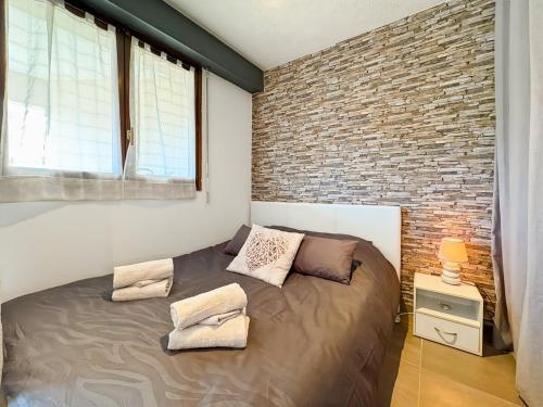 un lit dans une chambre avec un mur de briques dans l'établissement Cosy T1 à 5 minutes des plages, à Fréjus