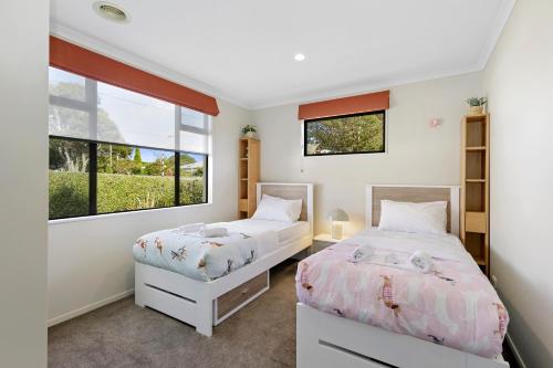 two beds in a room with two windows at Urban and Stunning 3 bed Home in Hutt Central in Lower Hutt