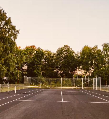 a tennis court with a net on top of it at Modern villa med spa och pool in Skäralid
