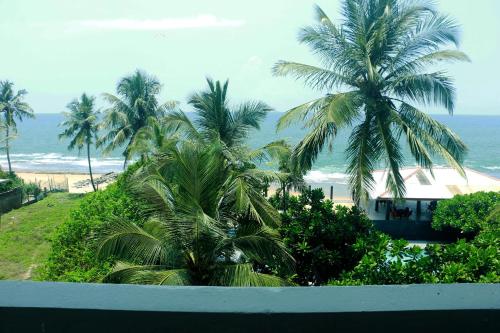 a view of a beach with palm trees and the ocean at Sea Shine Beach Hotel in Uswetakeiyawa