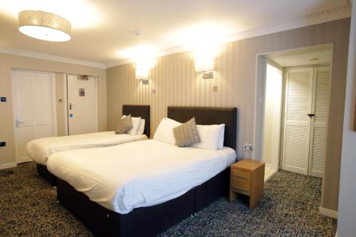 two beds in a hotel room with white sheets at Kelvingrove Hotel - Sauchiehall St in Glasgow