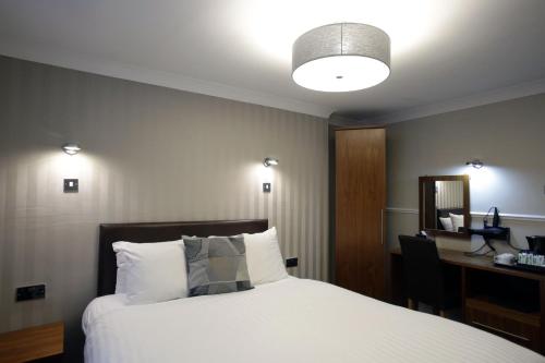 a bedroom with a bed and a desk with a mirror at Kelvingrove Hotel - Sauchiehall St in Glasgow
