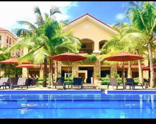 a resort with a swimming pool with chairs and umbrellas at San Remo Oasis in Cebu City