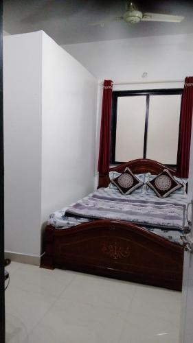 a bedroom with a wooden bed with a window at Om Datta Krupa Niwas Cottage in Mahabaleshwar