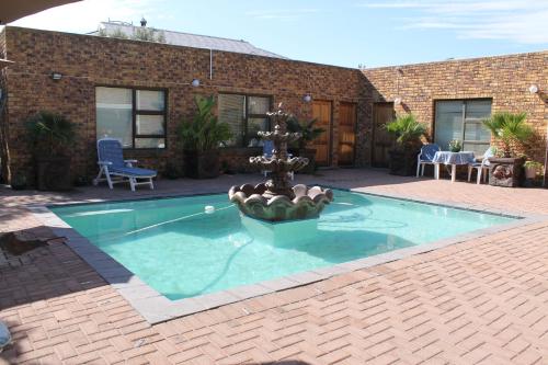 a swimming pool with a fountain in a yard at Quest Bed And Breakfast in Melkbosstrand
