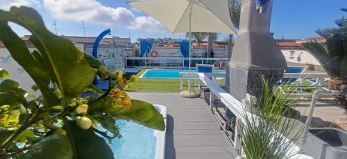 a patio with a pool and an umbrella and a plant at Alloggi Turistici con Piscina Palestra Jacuzzi Sauna - All Inclusive in Anzio