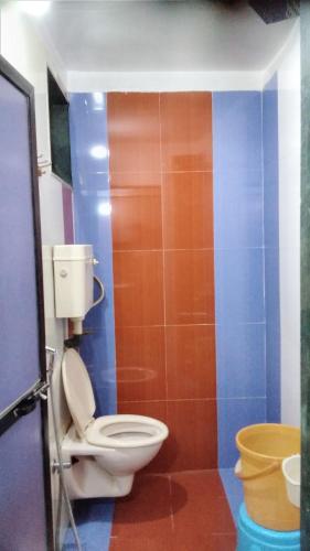 a bathroom with a toilet and a colorful wall at Om Datta Krupa Niwas Cottage in Mahabaleshwar