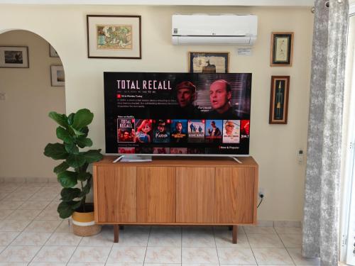 a flat screen tv sitting on top of a wooden entertainment center at Villa Best Holiday- breathtaking sea views, amazing garden, private pool, BBQ, next to CORAL BAY, Lower Peyia, Paphos in Peyia