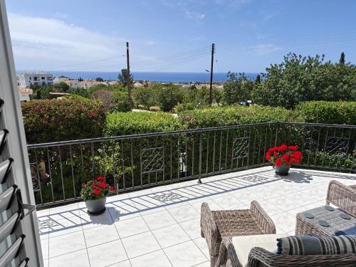 a balcony with two chairs and a table with flowers at Villa Best Holiday- breathtaking sea views, amazing garden, private pool, BBQ, next to CORAL BAY, Lower Peyia, Paphos in Peyia