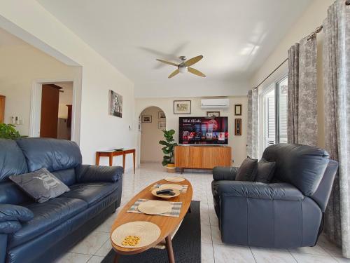 a living room with a blue couch and a table at Villa Best Holiday- breathtaking sea views, amazing garden, private pool, BBQ, next to CORAL BAY, Lower Peyia, Paphos in Peyia
