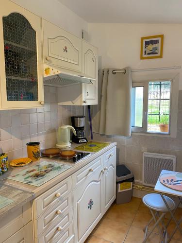 une cuisine avec des armoires blanches et un comptoir dans l'établissement Le bon coin, à Périssac