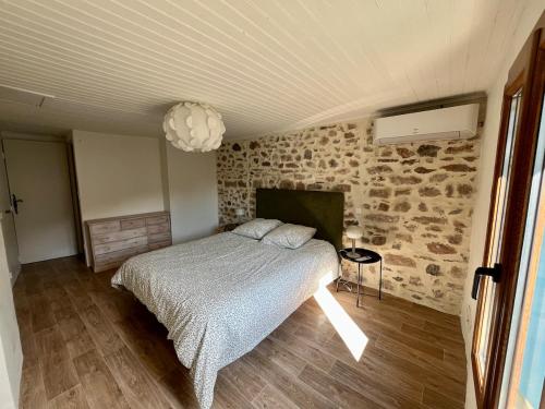 a bedroom with a bed and a stone wall at Charmante maison dans un hameau paisible in Salasc