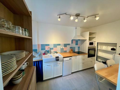 une cuisine avec des placards blancs et une table avec des assiettes dans l'établissement Charmante maison dans un hameau paisible, à Salasc