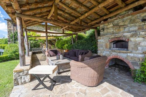 an outdoor patio with a stone fireplace and furniture at Villa Riflessi di Fiesole - Piscina - Vista Firenze in Fiesole