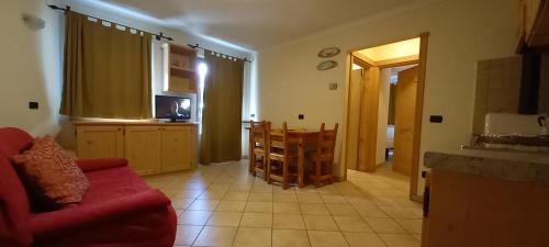 a living room with a red couch and a kitchen at Chalet La Rugiada in Bormio