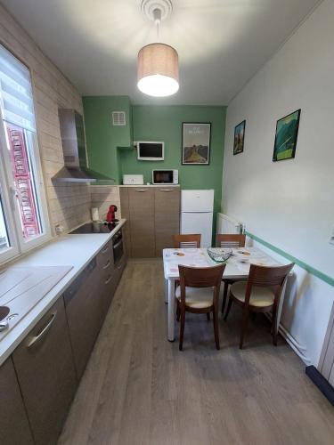 - une cuisine avec une table, des chaises et des murs verts dans l'établissement Charmant appartement - Le Mont Dore, à Le Mont-Dore
